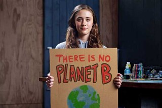 Une adolescente porte avec ses deux mains un écriteau en carton avec un message pour le respect de la planète